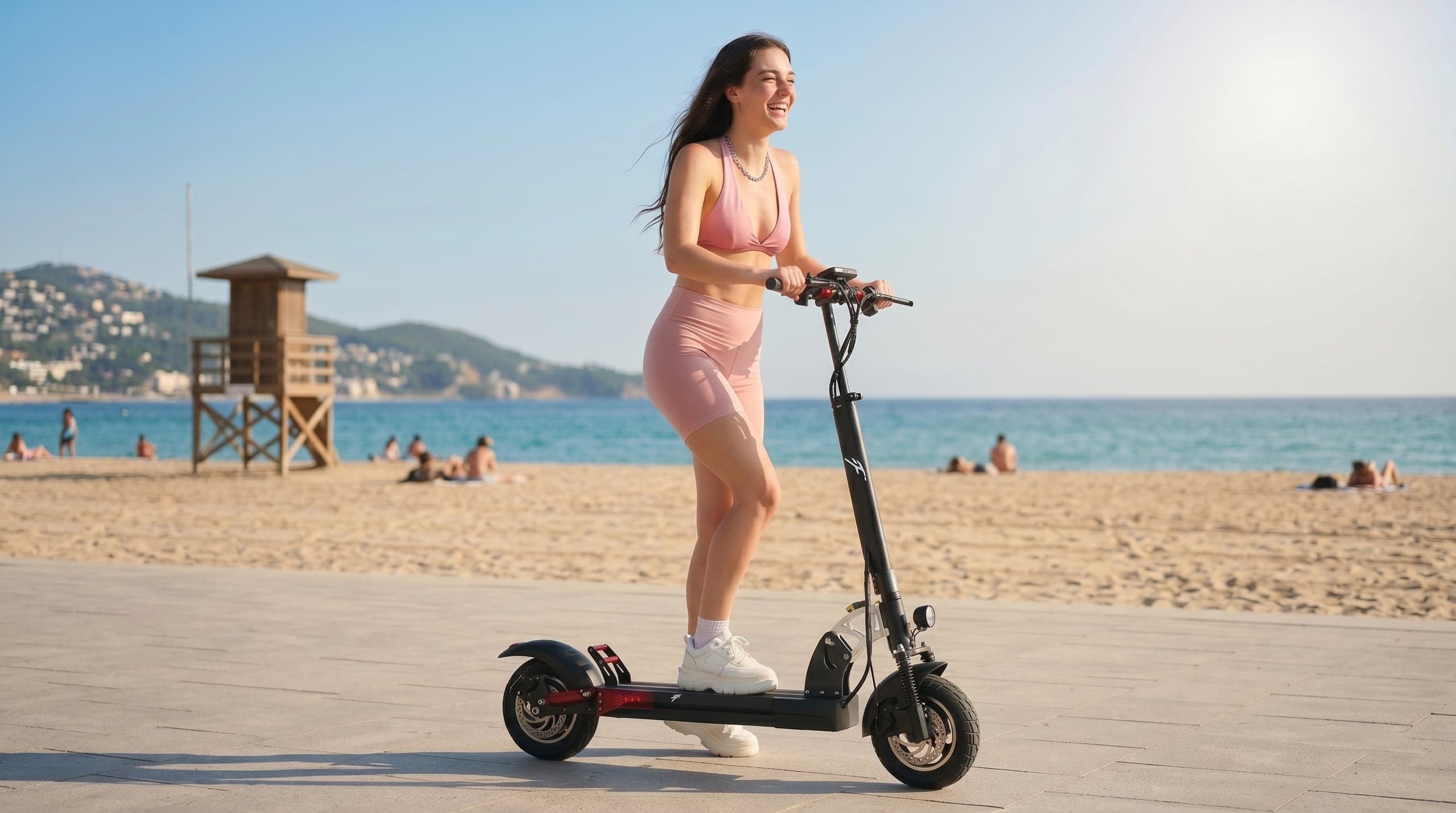 Rider smiling on an F1 scooter along a seaside boardwalk at midday
