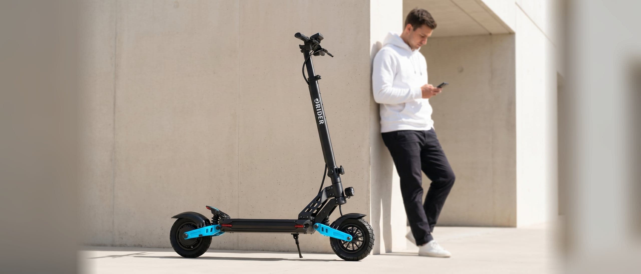 RIDER 10X PRO propped beside a rider in a modern concrete courtyard